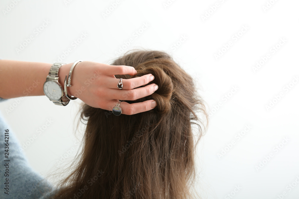 Fototapeta premium Beautiful young woman with stylish bijouterie doing her hair on white background