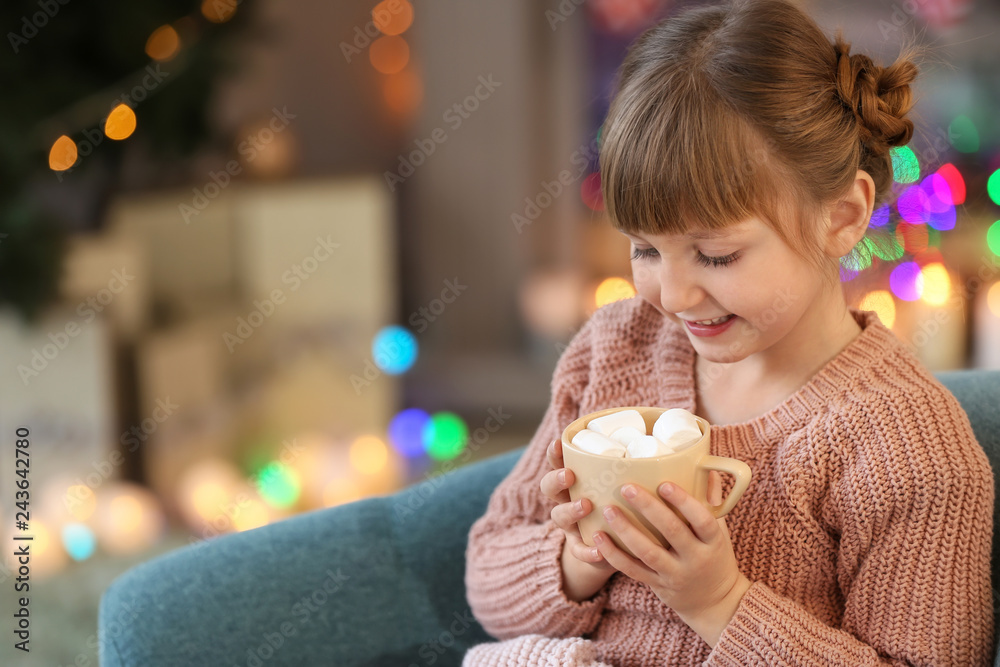 Cute little girl drinking hot chocolate at home on Christmas eve