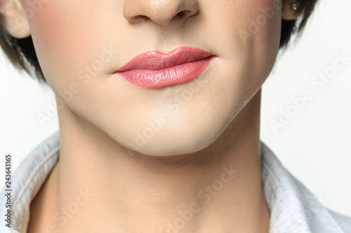 Young transgender man with pink lipstick on white background, closeup