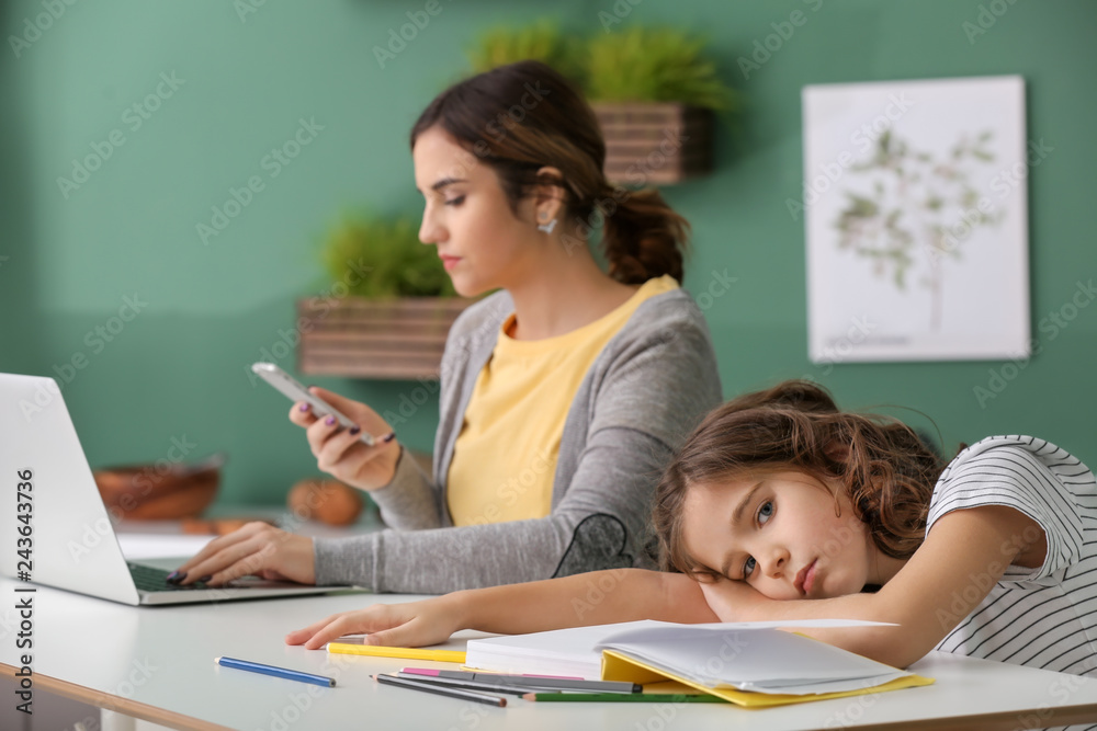 Busy mother with bored daughter working in kitchen at home Busy mother with bored daughter working in kitchen at home