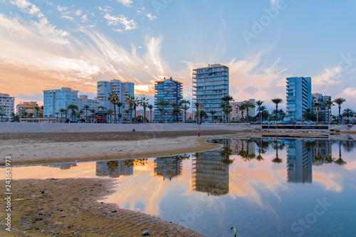 Reflexiones sobre el agua al atardecer. En una playa a al caer el dia sobre edificios de verano en la playa de San Juan, Alicante España
