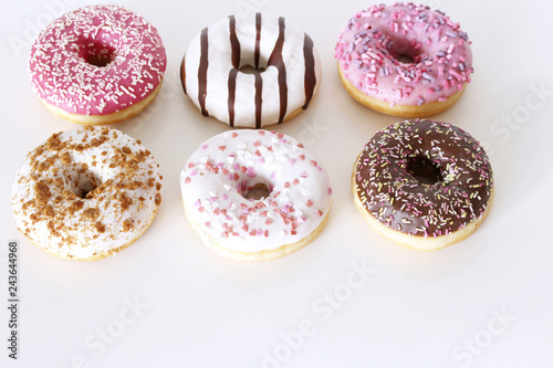 Traditional donuts on white wooden background. Tasty doughnuts with icing and powdered sugar, copy space.