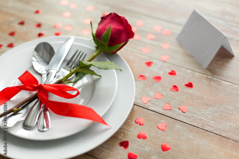 valentines day, table setting and romantic dinner concept - close up of red rose flower on set of dishes with cutlery, hearts and blank place card valentines day, table setting and romantic dinner concept - close up of red rose flower on set of dishes with cutlery, hearts and blank place card