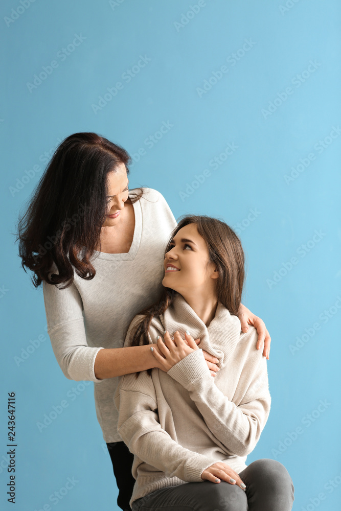 Portrait of young woman with her mother on color background
