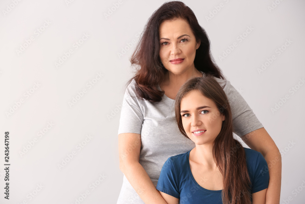 Portrait of young woman with her mother on light background Portrait of young woman with her mother on light background