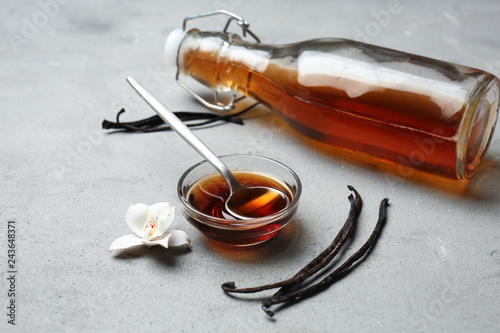 Glass bowl and bottle with vanilla extract on table