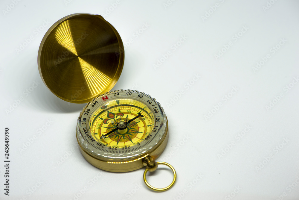 An old golden compass on a white background