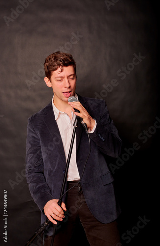 man sings on a dark background in the microphone