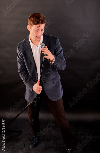 man sings on a dark background in the microphone