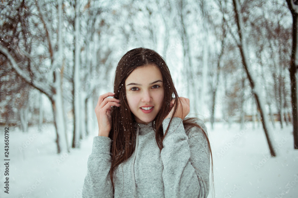 young beautiful caucasian girl in snow on background of winter park outdoors young beautiful caucasian girl in snow on background of winter park outdoors