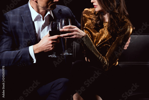 cropped view of couple clinking glasses of red wine isolated on black