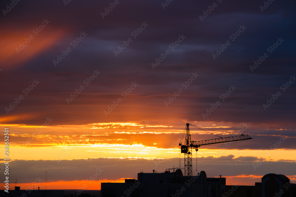 silhouette of construction crane and building on sunrise sky background