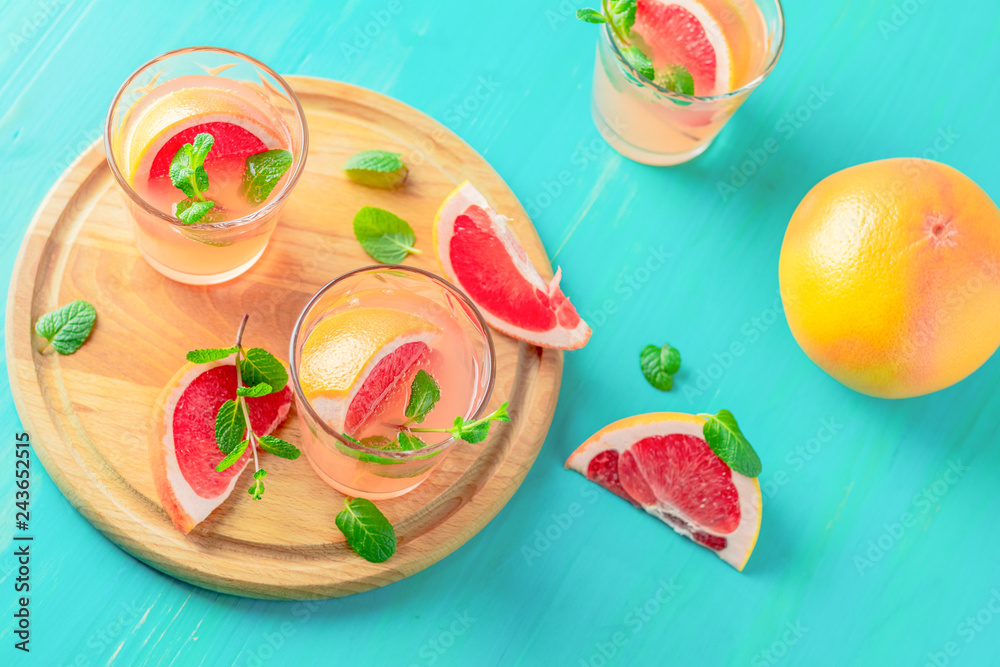 Pink alcoholic cocktail with grapefruit, ice and mint