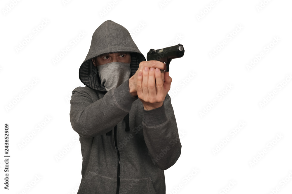 The man in a sports gray jacket and in a mask on a face shoots with the gun. White background The man in a sports gray jacket and in a mask on a face shoots with the gun. White background