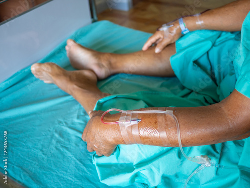 Close-up of senior asian man patient is receiving blood solution on bed in the hospital.