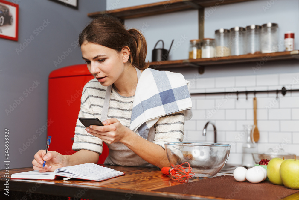 Happy young woman standing at the kitchen at home Happy young woman standing at the kitchen at home
