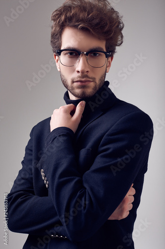 Handsome elegant man with curly hair wearing suit and glasses