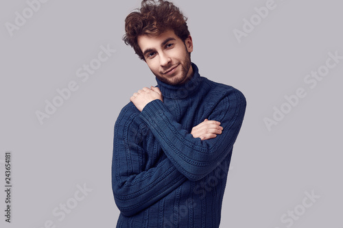 Handsome elegant man with curly hair in blue sweater © micro