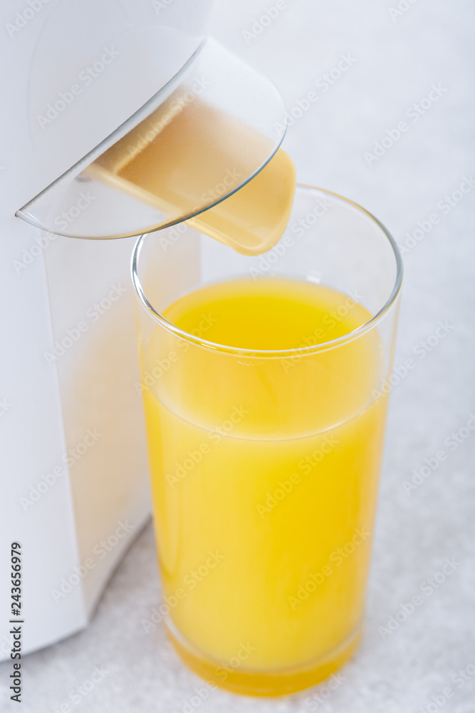 Juicer with a glass of fresh orange juice in a modern kitchen. Juicer with a glass of fresh orange juice in a modern kitchen.