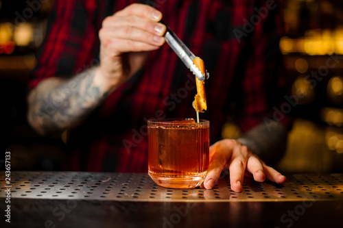 Bartender adding to a Old Fashioned cocktail orange zest © fesenko