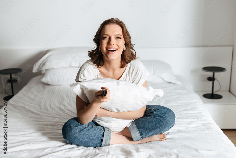 Attractive young woman sitting on bed at home