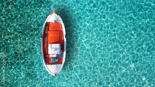 Aerial drone bird's eye top view of colourful traditional fishing boat in turquoise clear waters, Aegean sea, Greece