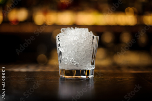Vintage cocktail glass of crushed ice standing on the empty bar stand
