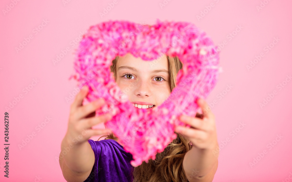 Fototapeta premium Love holiday decor. Love concept. Girl cute child show heart shaped decor. Symbol of love. Kid adorable girl with long hair happy face show heart to you. Look in heart part. Celebrate valentines day