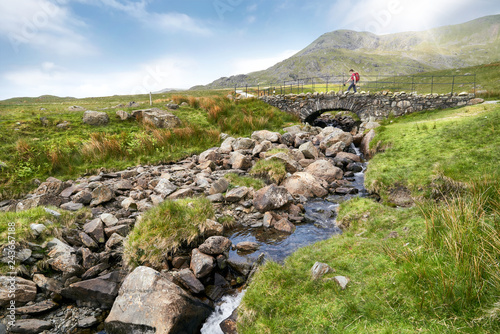 Obraz na płótnie A hiker crossing Torver Bridge near Coniston on a sunny summers day in the English Lake District. w salonie