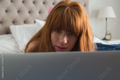 Woman using laptop in bedroom at home