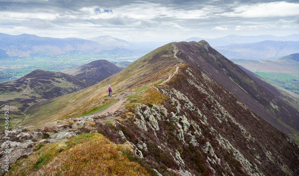 A hiker mountain walking in the English Lake District, UK. Descending Scar Crags and approaching Causey Pike. A hiker mountain walking in the English Lake District, UK. Descending Scar Crags and approaching Causey Pike.