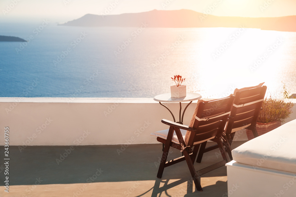 Beautiful sunset at Santorini island, Greece. Two chairs on the terrace with sea view