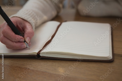 Woman writing on a diary at home