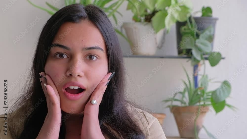 Beautiful young lady gives a shock expression with her hands on her pretty face and jaw wide open Beautiful young lady gives a shock expression with her hands on her pretty face and jaw wide open