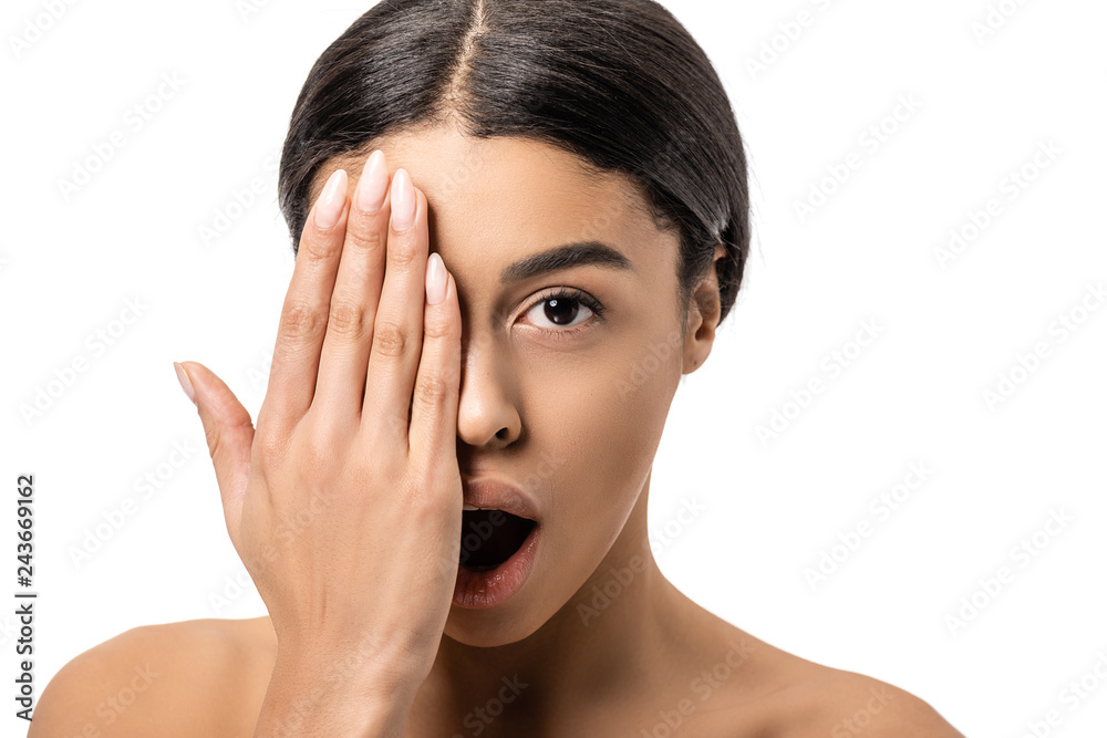 shocked young african american woman with open mouth closing eye with hand and looking at camera isolated on white shocked young african american woman with open mouth closing eye with hand and looking at camera isolated on white