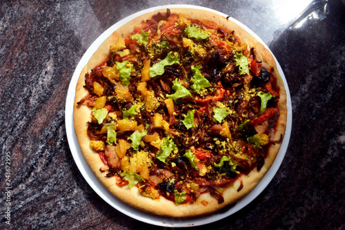 Thick, vegan pizza with tofu cheese, vegan soy sausages, mushrooms, capsicum, black olives, pineapple, tomatoes, lettuce and onions.