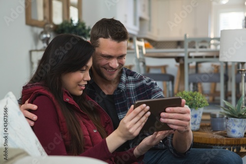 Couple using digital tablet in living room