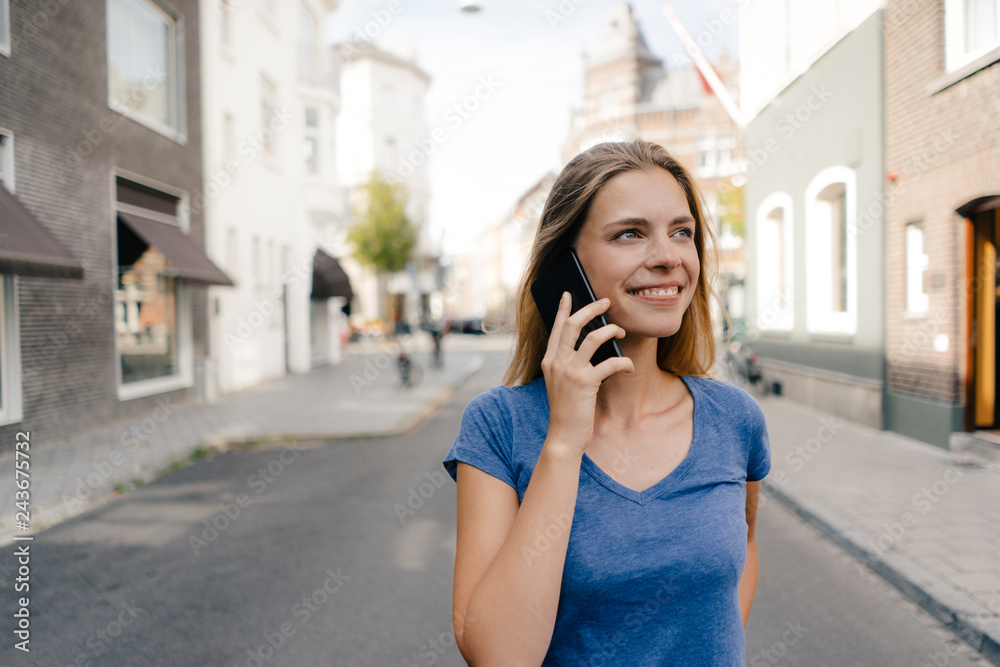 Netherlands, Maastricht, smiling young woman on cell phone in the city