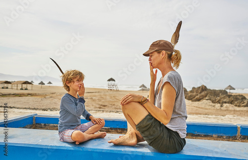 Chile, Arica, mother sitting with son on wall on the beach photo