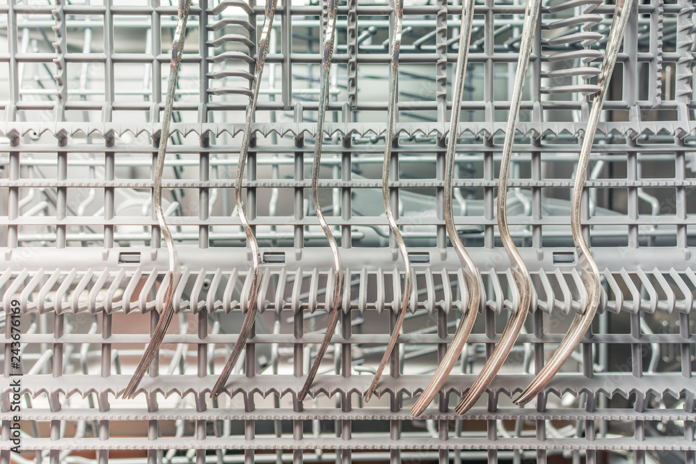 Silver forks lie in the upper compartment of the dishwasher Silver forks lie in the upper compartment of the dishwasher