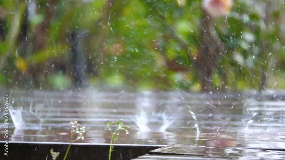 Close up slow motion video of raining drop splashing in the wooden footway on blur background (High Speed Video) Close up slow motion video of raining drop splashing in the wooden footway on blur background (High Speed Video)