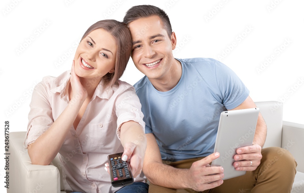Smiling Couple Using Remote Control and Tablet