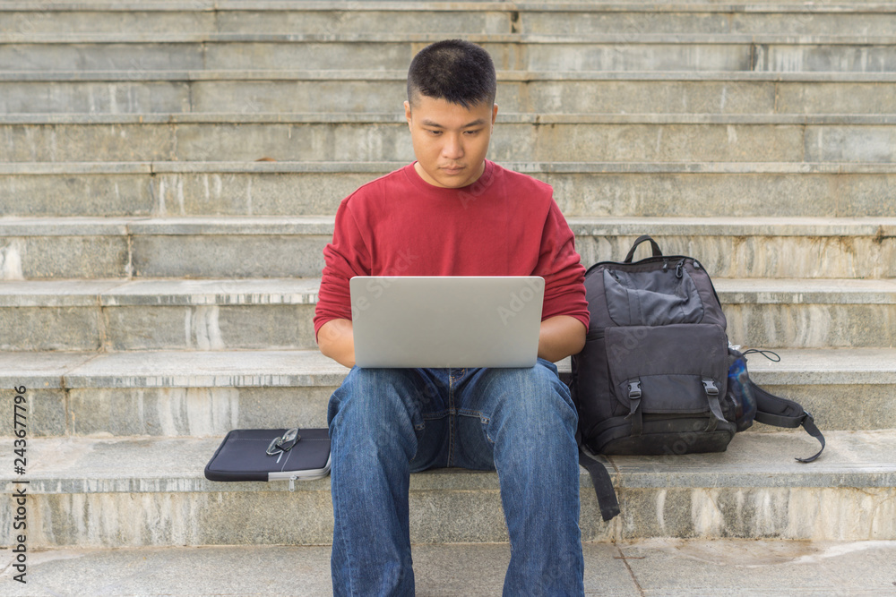Male student sitting on stair steps and using laptop Male student sitting on stair steps and using laptop