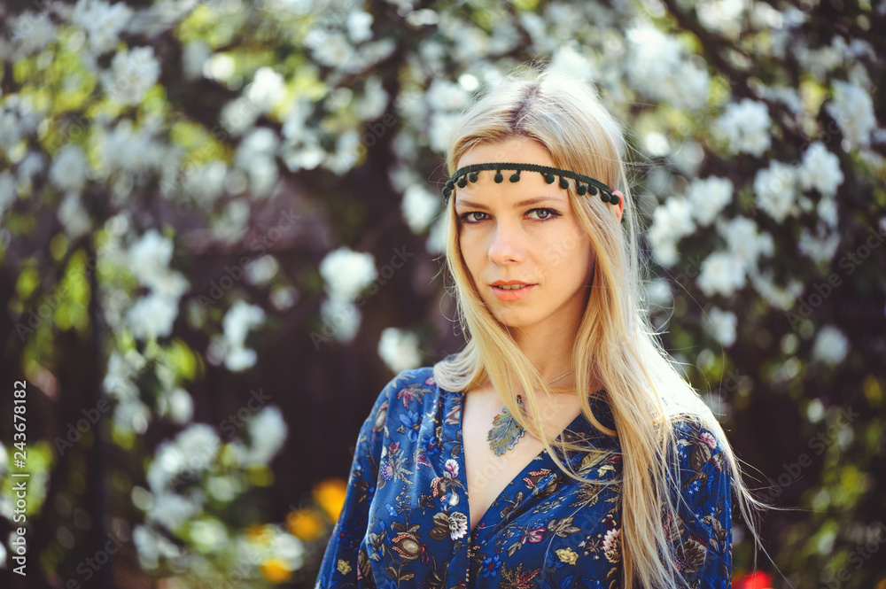 Portrait of young beautiful women smiling in the flowered garden in the spring time. Almond flowers are blooming. The girl is dressed stylishly, jewelry on her head. Portrait of young beautiful women smiling in the flowered garden in the spring time. Almond flowers are blooming. The girl is dressed stylishly, jewelry on her head.