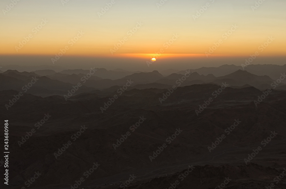 Magic golden sunrise in the mountains. The sun comes out from the cloud. View from Mount Sinai (Mount Horeb, Gabal Musa, Moses Mount). Sinai Peninsula of Egypt