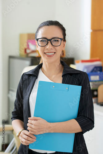 Cheerful Asian business lady holding clipboard with files for work photo