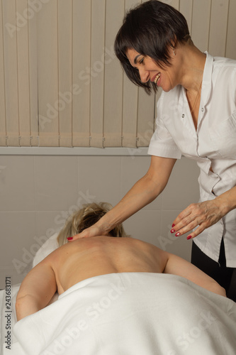 A happy woman is relaxing receiving a massage in a spa salon