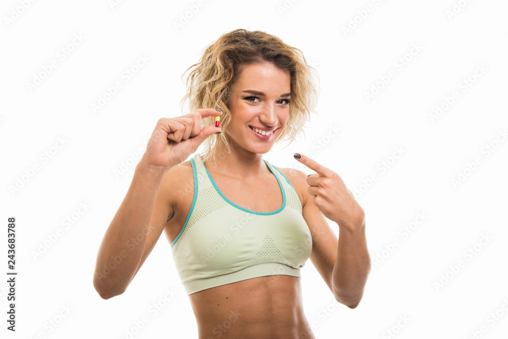 Portrait of beautiful young fit girl showing one pill Portrait of beautiful young fit girl showing one pill