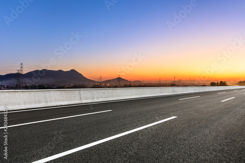 Empty asphalt road and mountains at beautiful sunset