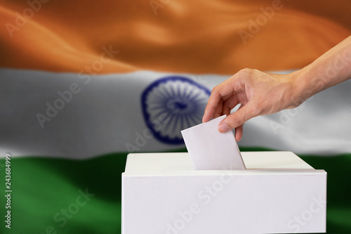 Konstfotografi Close-up of human hand casting and inserting a vote and choosing and making a decision what he wants in polling box with India flag blended in background